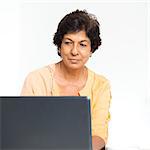 Older people and modern technology concept. Portrait of a 50s Indian mature woman using laptop computer at home. Indoor senior people living lifestyle.