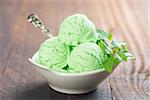 Scoop of pistachio ice cream in bowl on rustic old wooden vintage background.