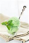 Scoop of green tea ice cream in cup on wooden vintage background.