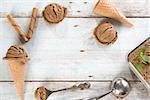 Top view brown ice cream in waffle cone with utensil on rustic wooden background. Copy space on middle.
