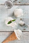 Top view vanilla ice cream in waffle cone with utensil on wood background.