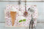 Top view scoop coconut ice cream in waffle cone with utensil, spoon and color rice on wood background.