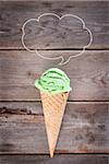 Single green tea ice cream in a waffle cone over old rustic wooden vintage background with copy space on top.