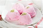 Scoops pink ice cream on plate at table background.