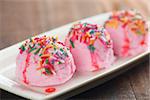 Pink ice cream on plate, decor with colorful rice, on old wooden vintage table background.