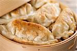 Close up fresh pan fried dumpling on bamboo basket. Chinese food with hot steams on rustic vintage wooden background.