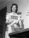 1950s 1960s SMILING HOUSEWIFE WEARING AN APRON LOOKING AT CAMERA USING AN ELECTRIC HAND MIXER