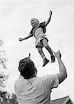 1950s 1960s FATHER TOSSING HIS SON UP INTO THE AIR