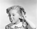 1950s LITTLE GIRL MAKING RUDE GESTURE STICKING OUT TONGUE CUPPING HAND ON EAR