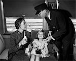 1950s MOTHER AND DAUGHTER ON TRAIN WITH CONDUCTOR PUNCHING THEIR TICKET