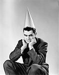 1950s DISGUNTLED MAN WEARING DUNCE CAP LOOKING AT CAMERA