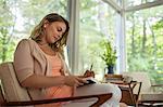 A woman seated holding an open journal and a pen.