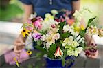 A person arranging a bunch of flowers in a vase.