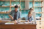 Young daughter drawing ar kitchen counter while parents prepare meal