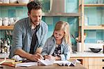 Father and young daughter drawing in kitchen