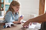 Little girl learning how to make paper airplane