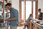 Family in kitchen, man drying dishes in foreground