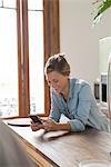 Young woman using smartphone in kitchen