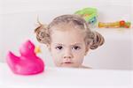 Little girl sitting in bath with unhappy expression, portrait
