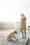 Young woman standing in the playground with her dog, Munich, Bavaria, Germany