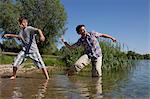 Father and son skipping rocks on lake