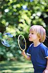 Boy blowing oversized bubble in backyard