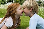 Children touching noses in field