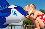 Girl kissing inflatable whale on dock