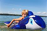 Boy floating in lake with toy whale