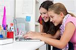Girls using laptop together at desk