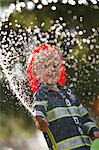 Boy in fireman costume playing with hose