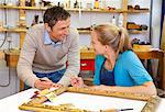 Carpenter and assistant working in shop