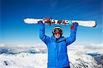 Child holding skis on snowy mountaintop