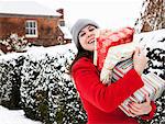 Woman carrying wrapped gifts in snow