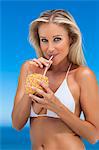 Woman drinking from pineapple outdoors