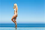 Woman wearing bikini by infinity pool