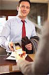 Businessman paying at hotel front desk