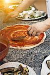 Chef spreading sauce on pizza dough