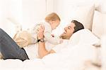 Father and young son relaxing together on bed, laughing