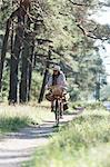 Woman cycling on forest path with foraging baskets