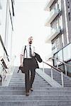 Businessman carrying jacket moving down city stairway