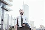 Stylish bearded  businessman carrying jacket walking in city