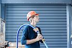 Factory engineer carrying power cable over his shoulder