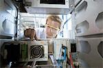 Factory technician inspecting machine electronics