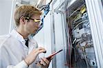 Factory technician inspecting equipment using digital tablet