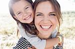 Portrait of mature woman giving daughter piggy back in park