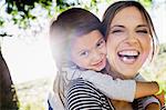 Portrait of mature woman giving daughter piggy back in sunlit park