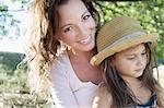 Portrait of mature woman and daughter wearing straw hat in park