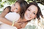 Portrait of mature woman giving daughter piggy back in park