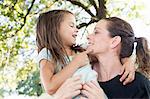 Mature woman carrying daughter in arms in park